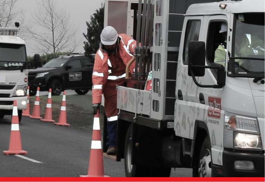 Pro-Tect truck with staff placing traffic cones down on the road